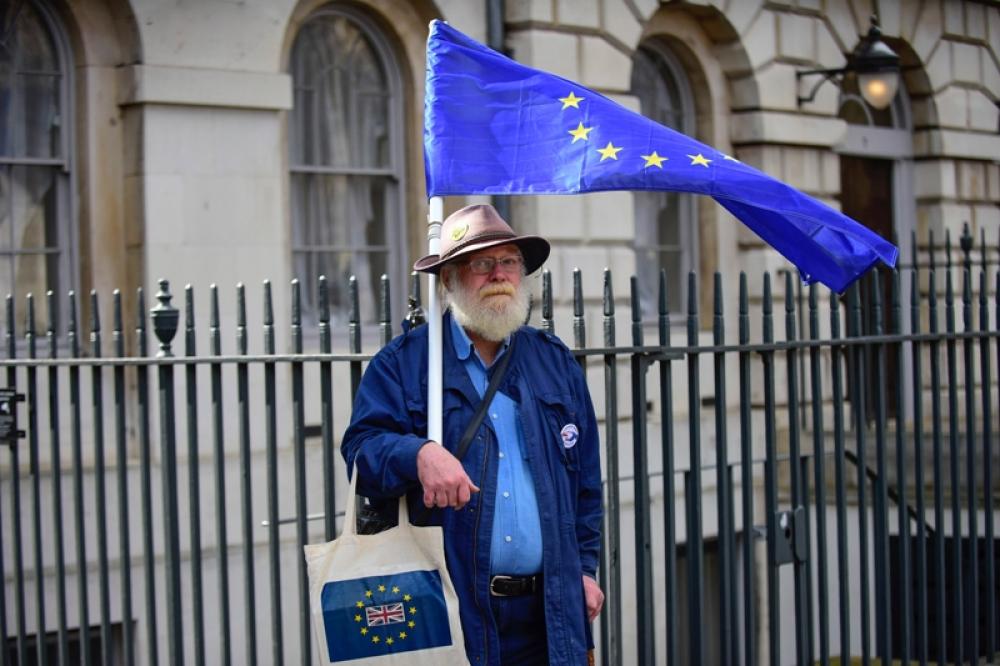 Anti-Brexit protester holds EU flag outside Parliament in London