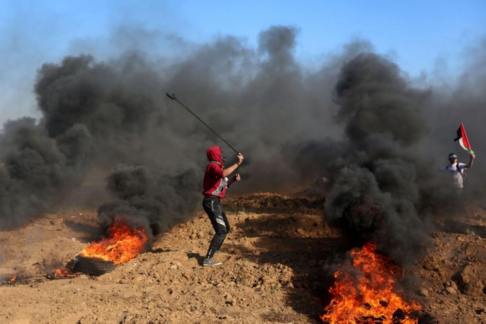 Palestinian protester hurls stones at Israeli troops