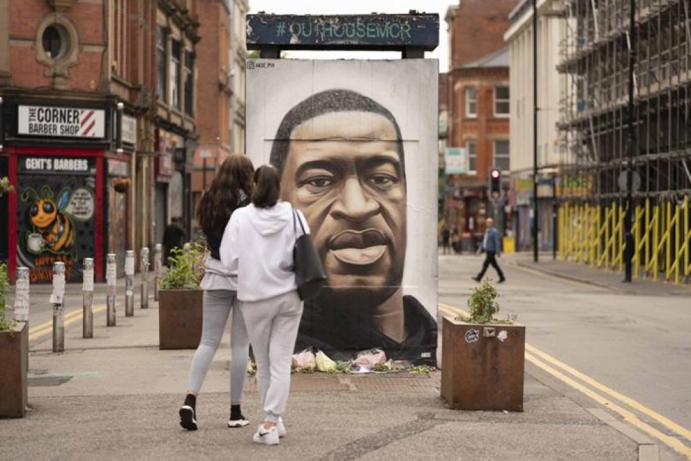 People gather by a mural of George Floyd in UK