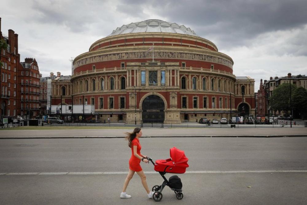 A woman walks past the Royal Albert Hall in London