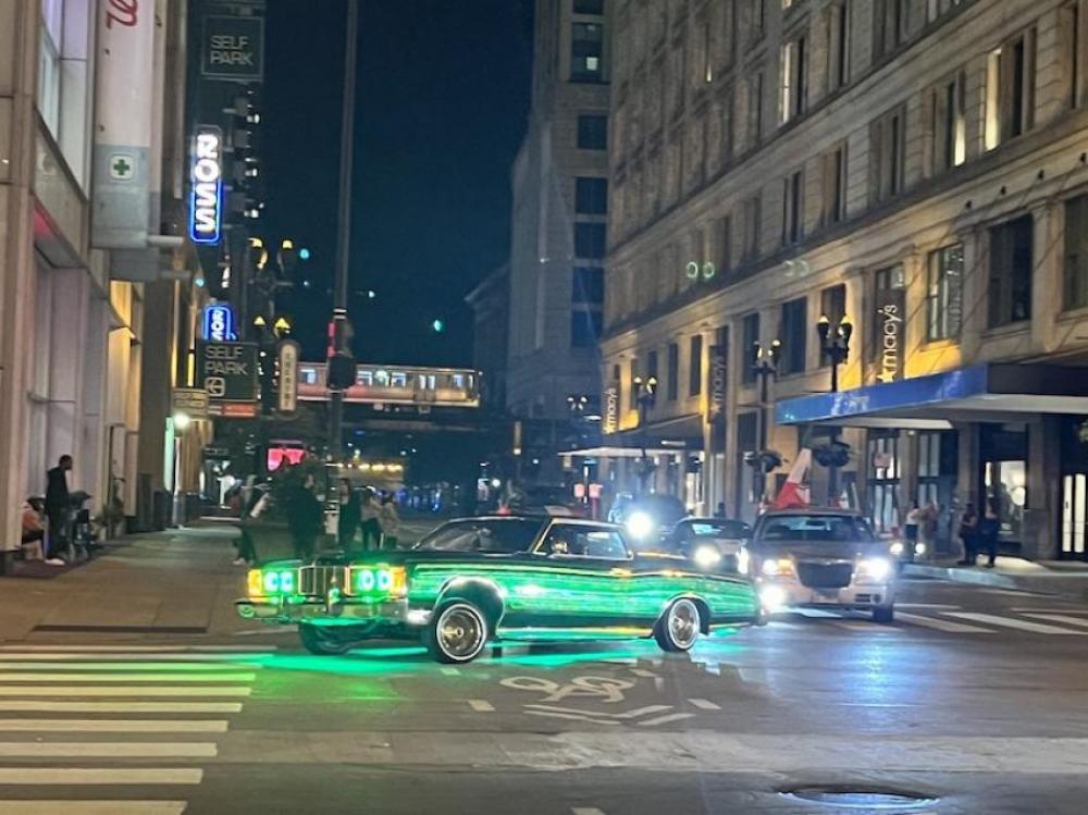 Midnight filming in the Chicago theatre district. A fancy blazing green car with strange wheel sizes on one side clambered through the street.